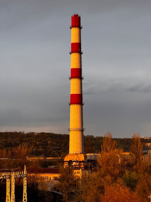 A large red and white chimney with a sunset in the background