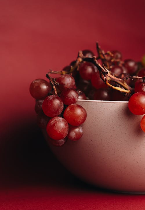 A bowl of grapes on a red background