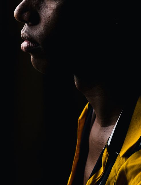 Artistic side profile portrait of a person wearing yellow, captured with dramatic lighting.