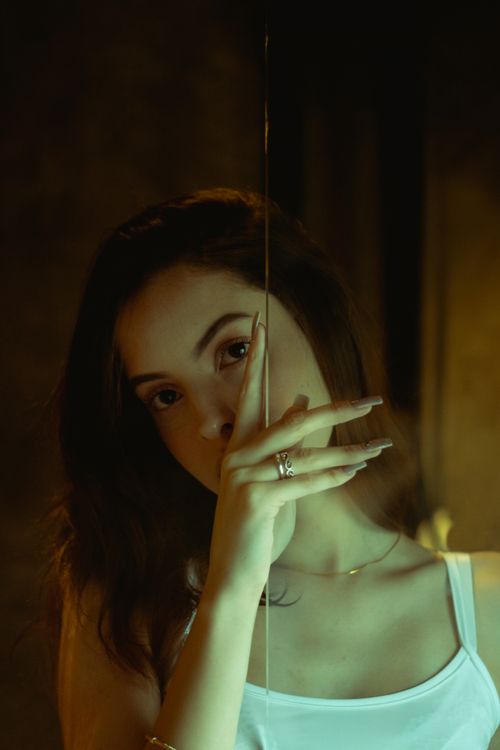 Free Elegant portrait of a woman with long hair, striking a thoughtful pose indoors with soft lighting. Stock Photo