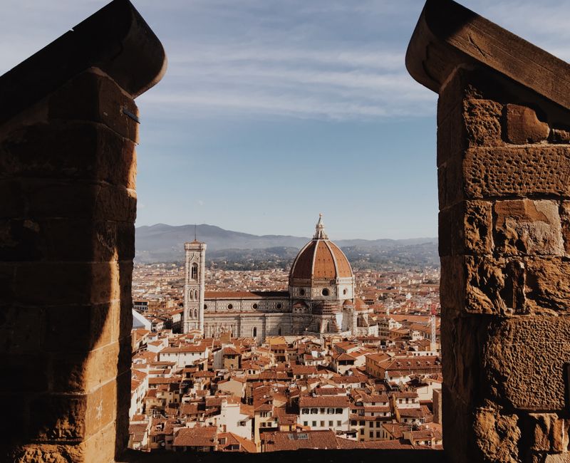 A breathtaking view of Florence Cathedral framed by ancient stone walls under clear blue skies.