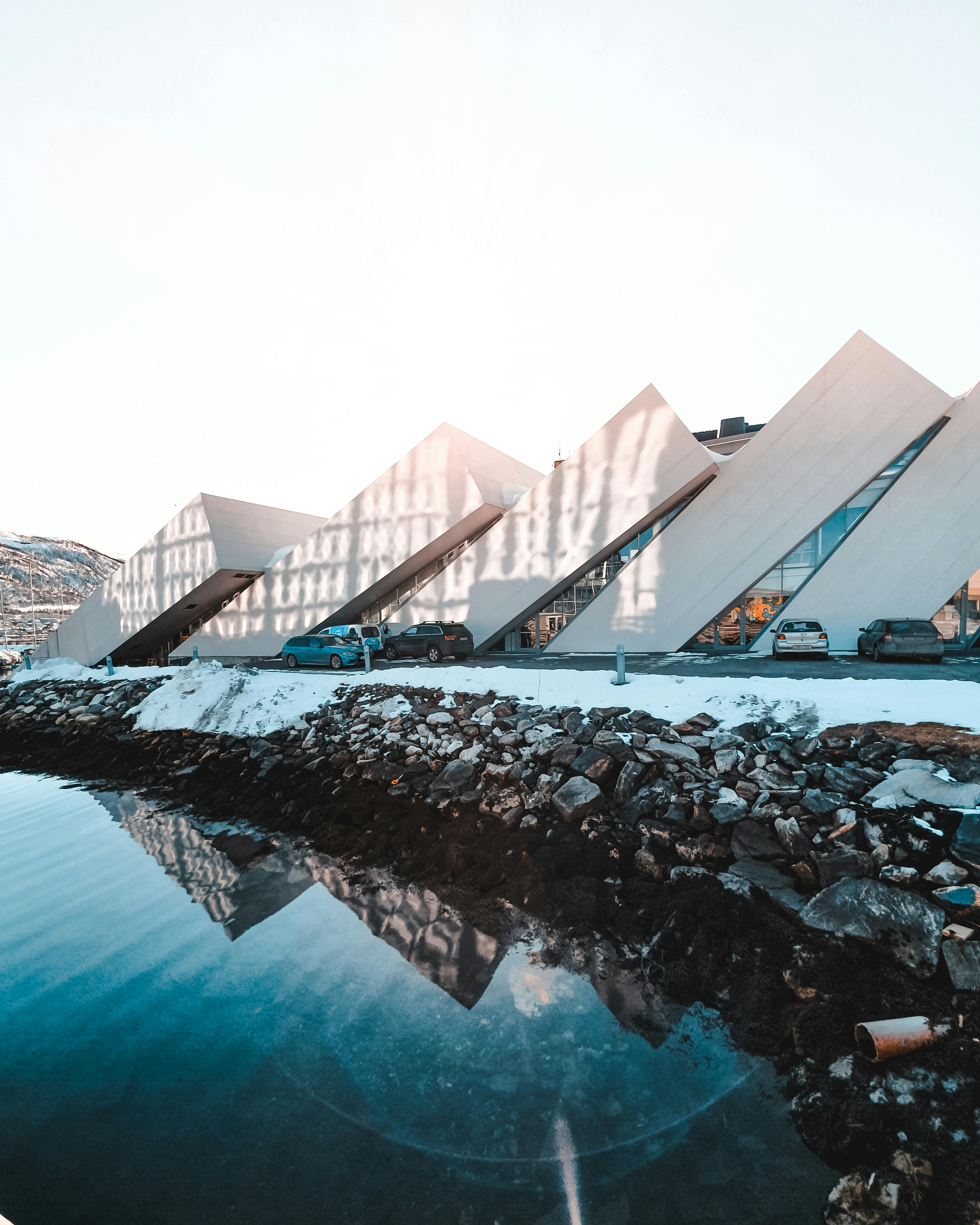 平静的水边倒映着现代几何建筑，背景是冬季