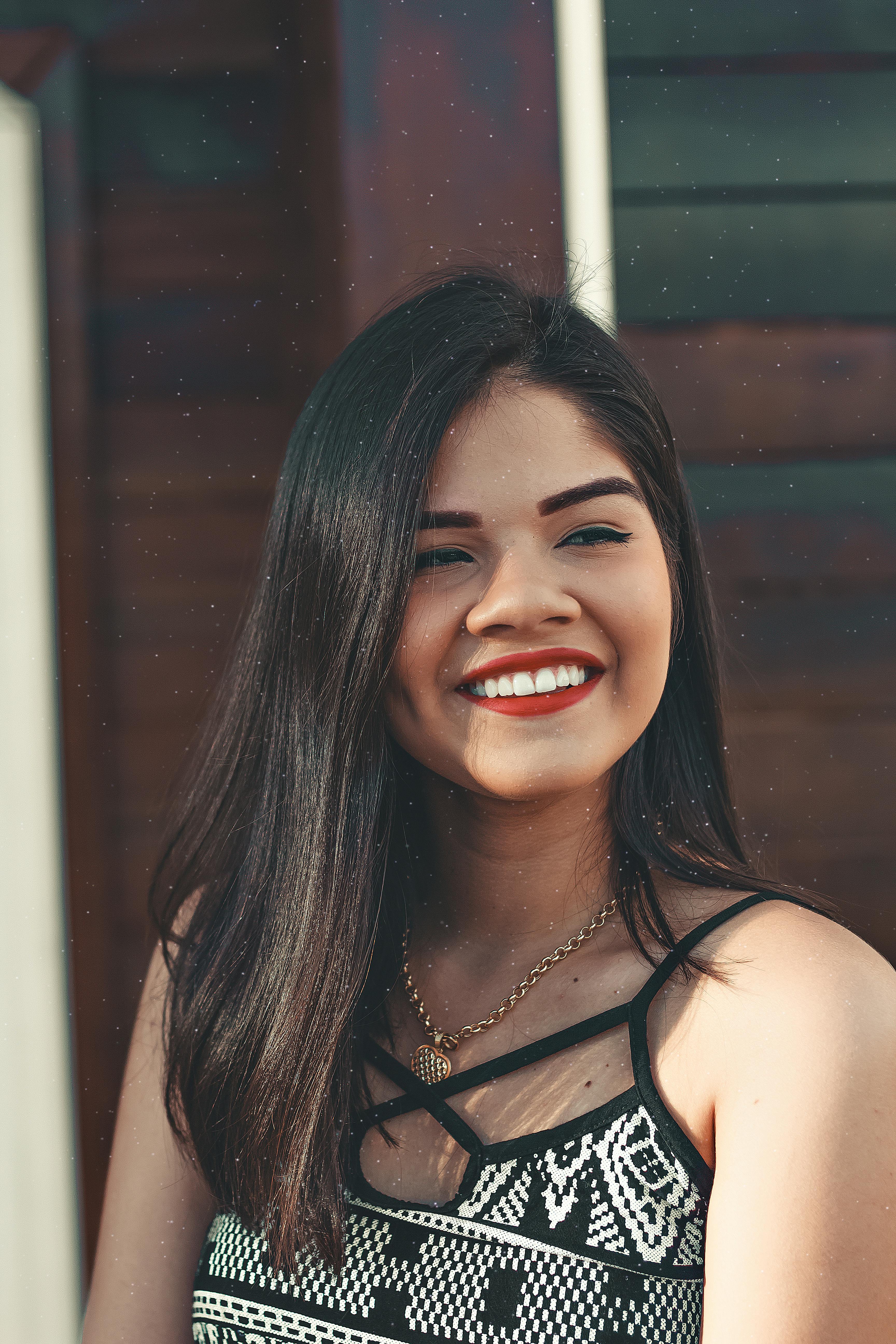 一位开朗的深色长发女子，在阳光明媚的户外微笑着