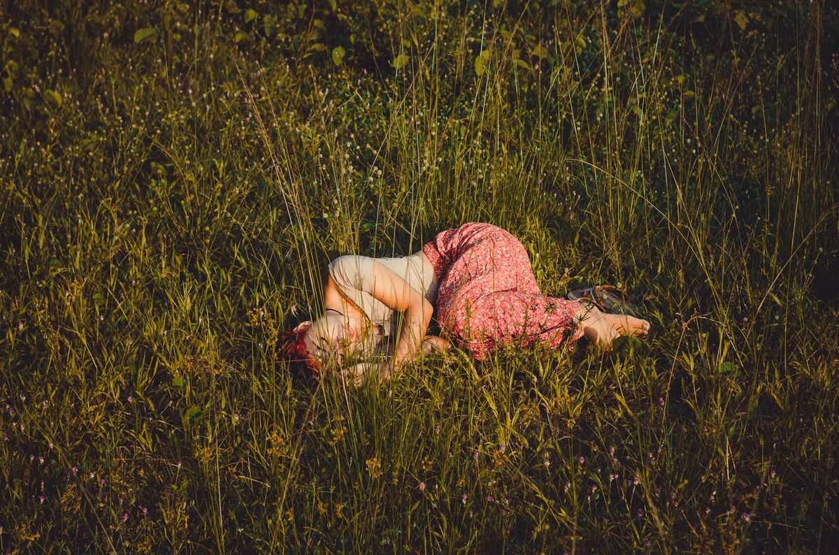 Woman resting in long meadow grass in a printed summer dress — photo by Italo Melo on Pexels