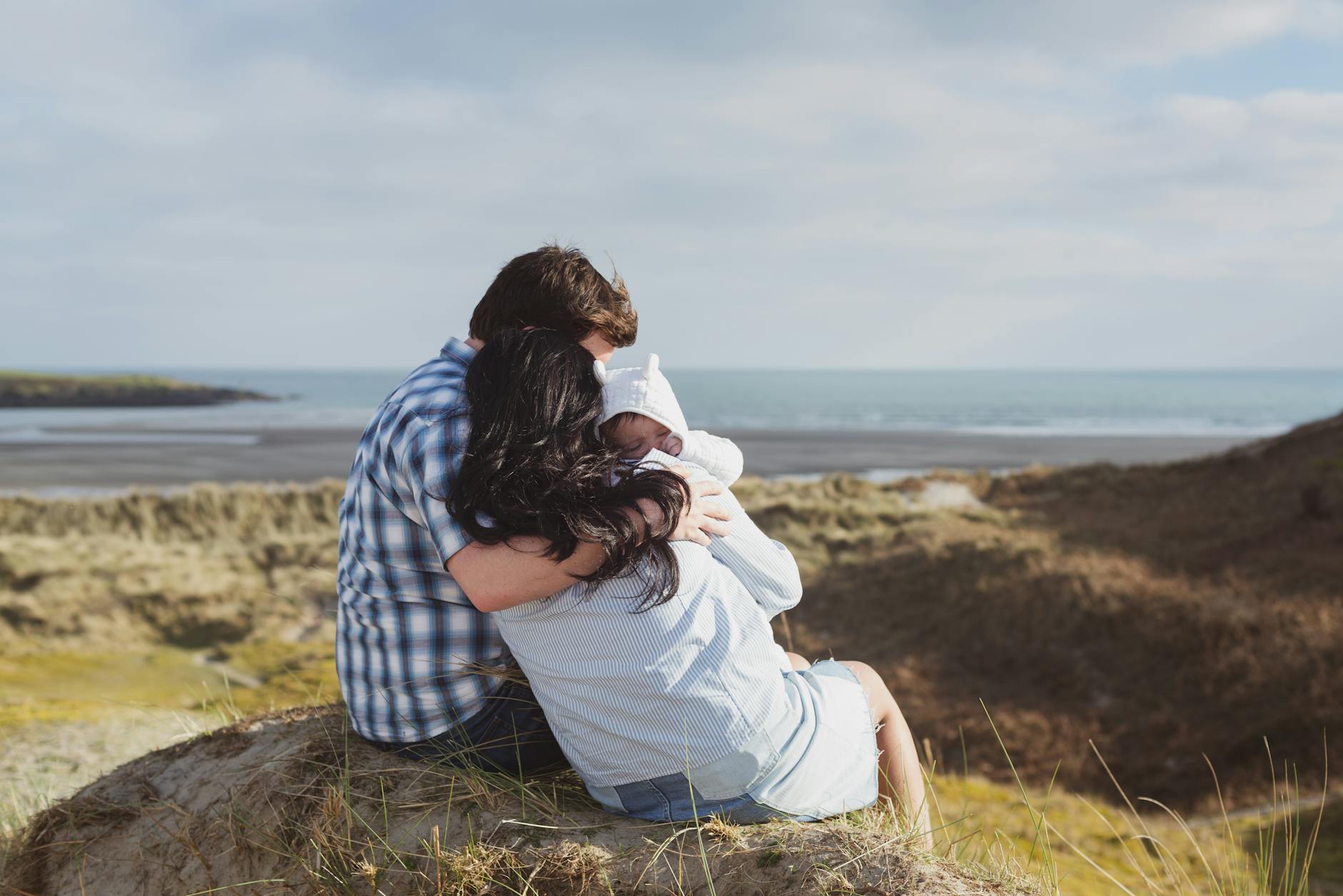 A family enjoying a serene moment with their newborn on Inchydoney Beach, Ireland.