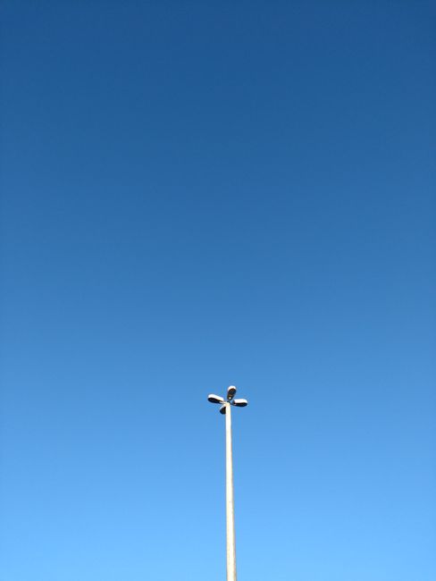A minimalist image of a lamppost standing against a clear blue sky, capturing the essence of simplicity.