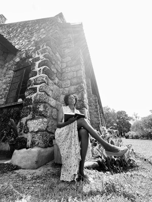 A woman sitting on a bench in front of a stone building