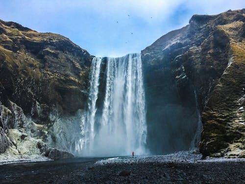 Free A person standing in front of a waterfall Stock Photo