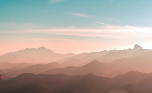 A sunset over mountains with a blue sky