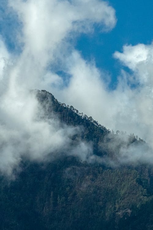 A mountain with clouds above it and a blue sky