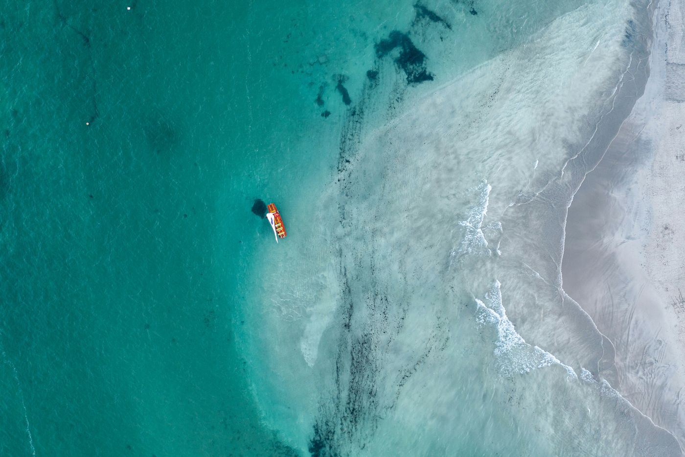 A lone sailboat on turquoise coastal waters