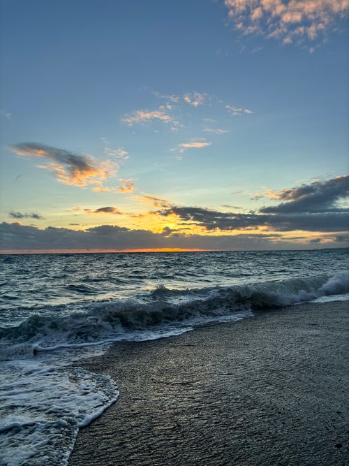 Free Calm ocean waves under a vivid sunset sky, creating a tranquil seaside atmosphere. Stock Photo