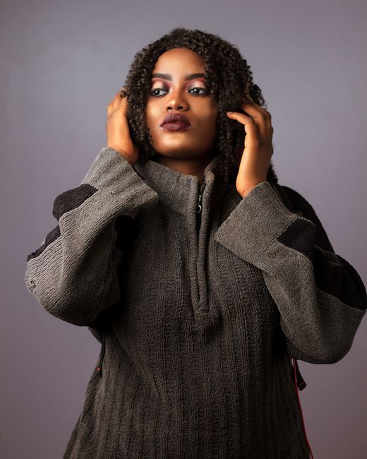 Elegant portrait of a woman posing confidently in a warm sweater with curly hair.