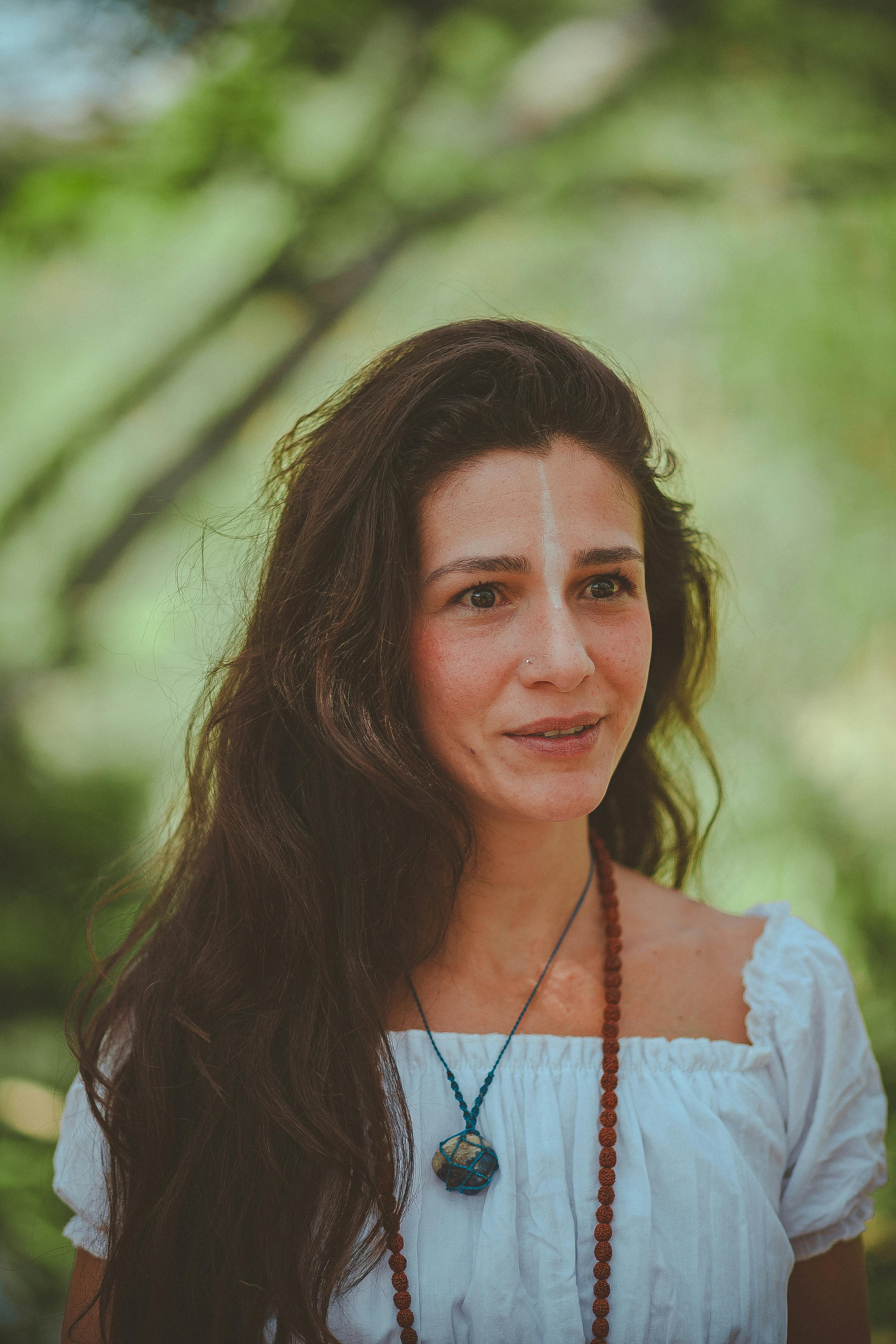 Portrait of a woman outdoors with serene expression and natural surroundings.