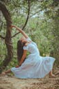 一名女子身穿白色连衣裙，在宁静的森林中练习瑜伽