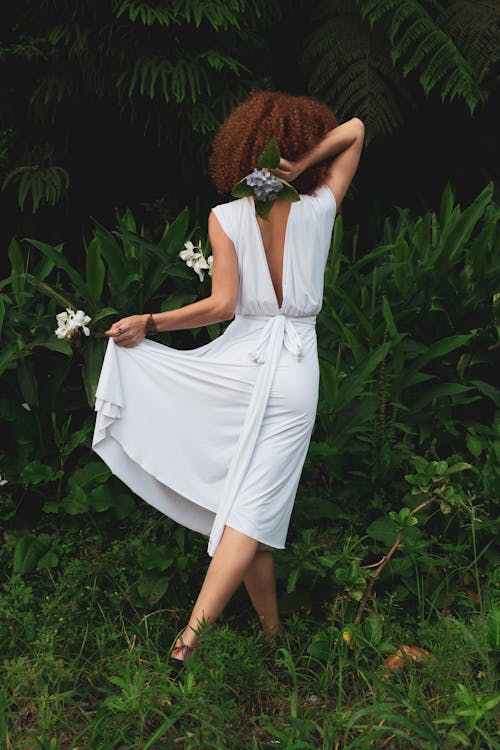 無料 植物の横に立っている白いドレスを着ている女性 写真素材