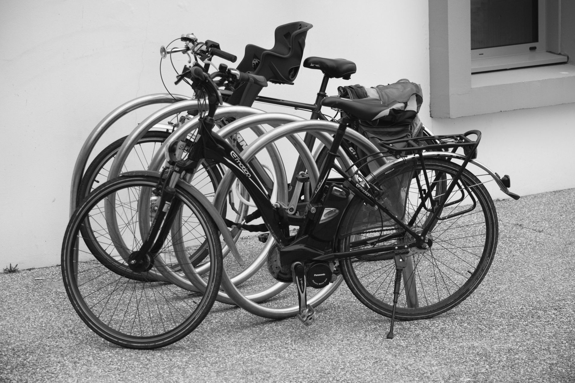 Monochrome image of electric bikes parked against a wall in an urban setting.
