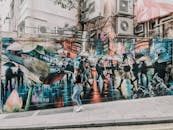 香港街头色彩缤纷的壁画描绘了城市生活，一名女子走过充满活力的街头艺术