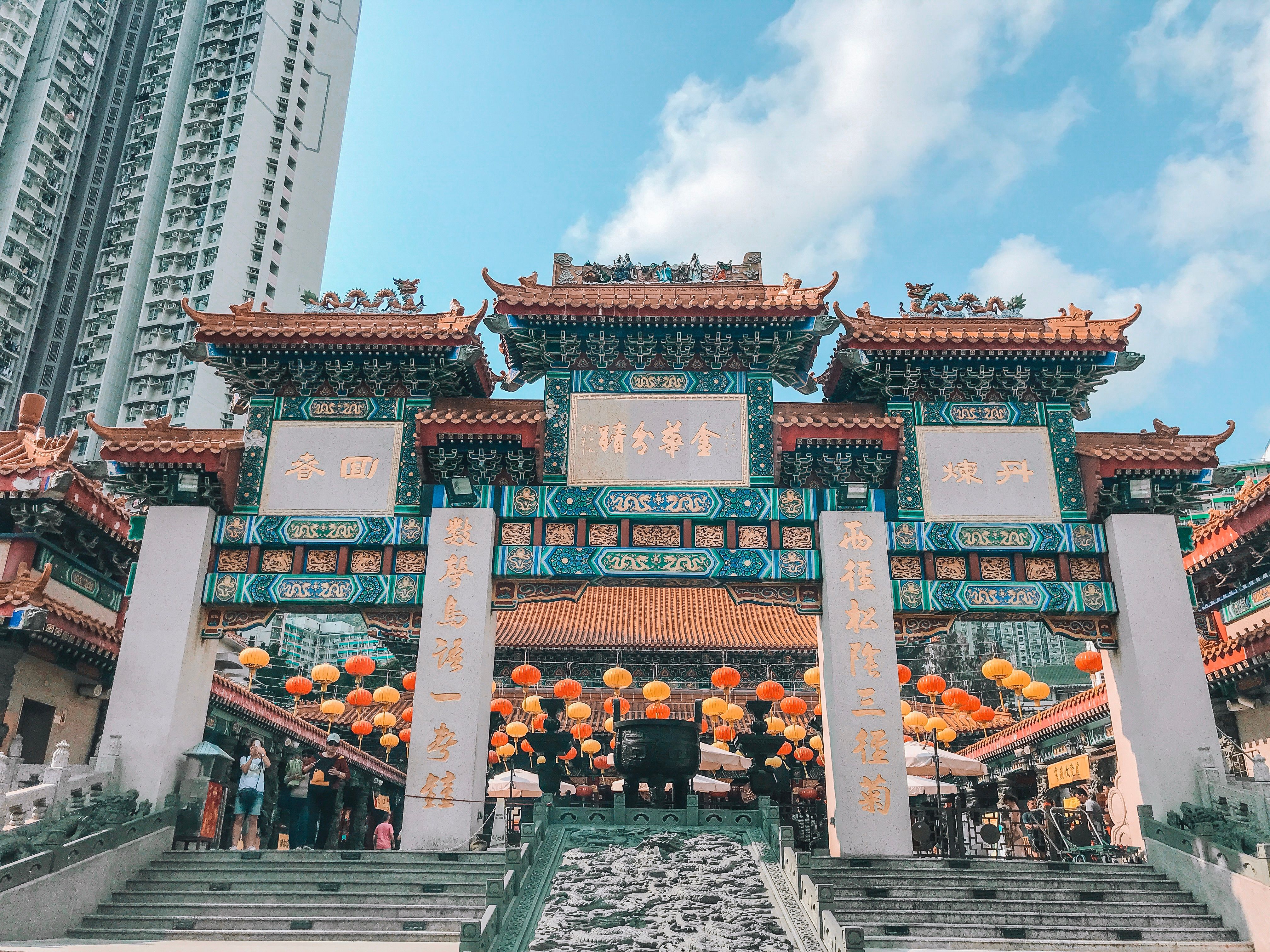 Vibrant Chinese architecture at Wong Tai Sin Temple in Hong Kong with lanterns and people.