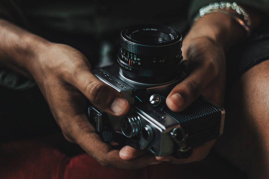 Detailed close-up of hands holding a vintage manual focus camera, showcasing classic photography equipment.