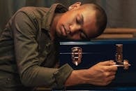 一位男子将头枕在蓝色盒子上的宁静肖像，传达出平静与时尚感