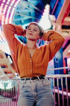 Woman in orange sweater enjoying the vibrant lights at São Paulo amusement park.