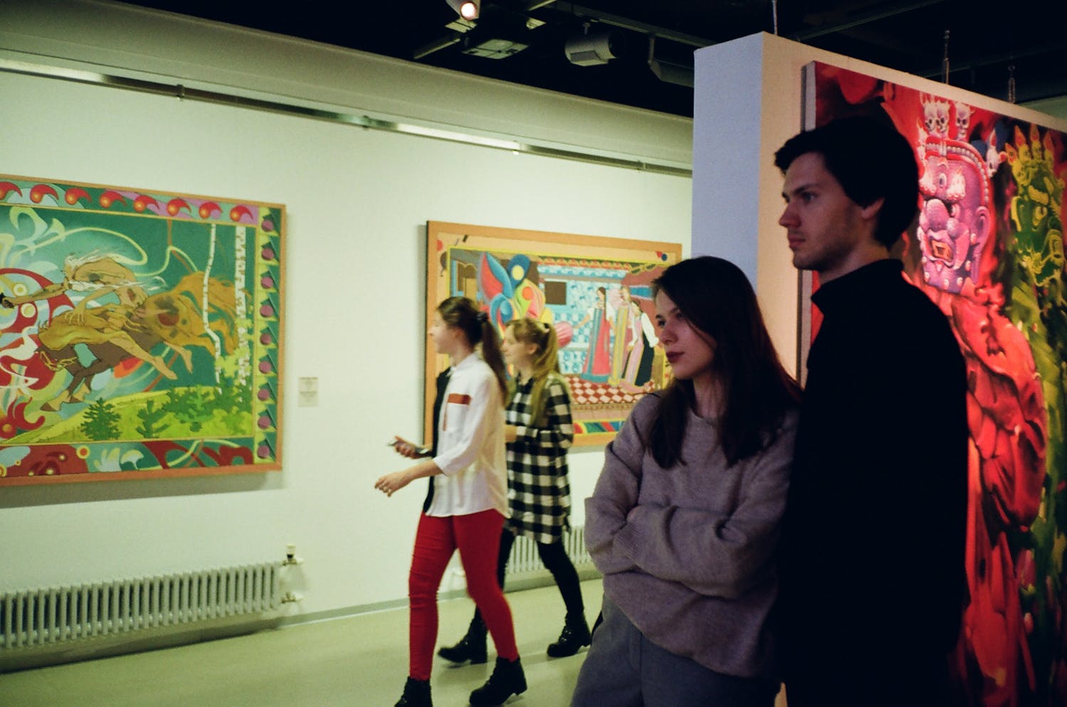 Visitors engaged with vibrant art pieces in a St. Petersburg gallery, showcasing modern creativity.