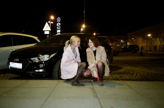 在圣彼得堡，两名女子坐在停在城市灯光下的汽车旁，享受着夜晚的外出时光