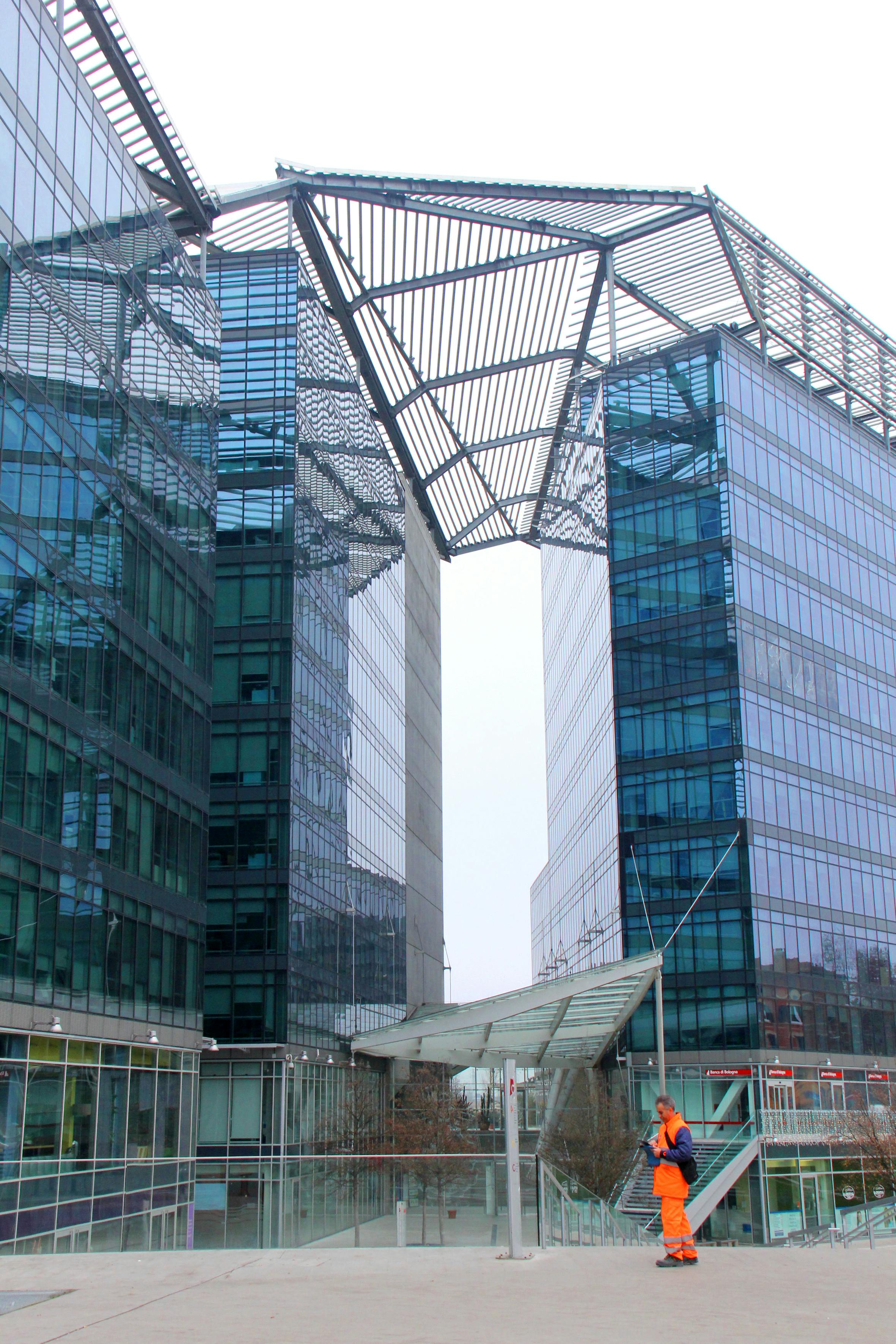 在一座现代化的玻璃建筑前，一名身穿鲜艳橙色服装的城市工人