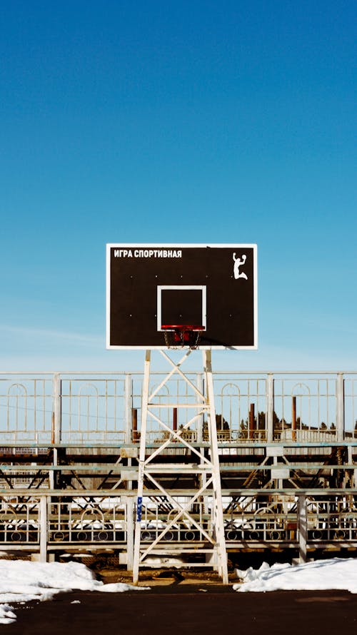 A basketball hoop in the snow with a blue sky