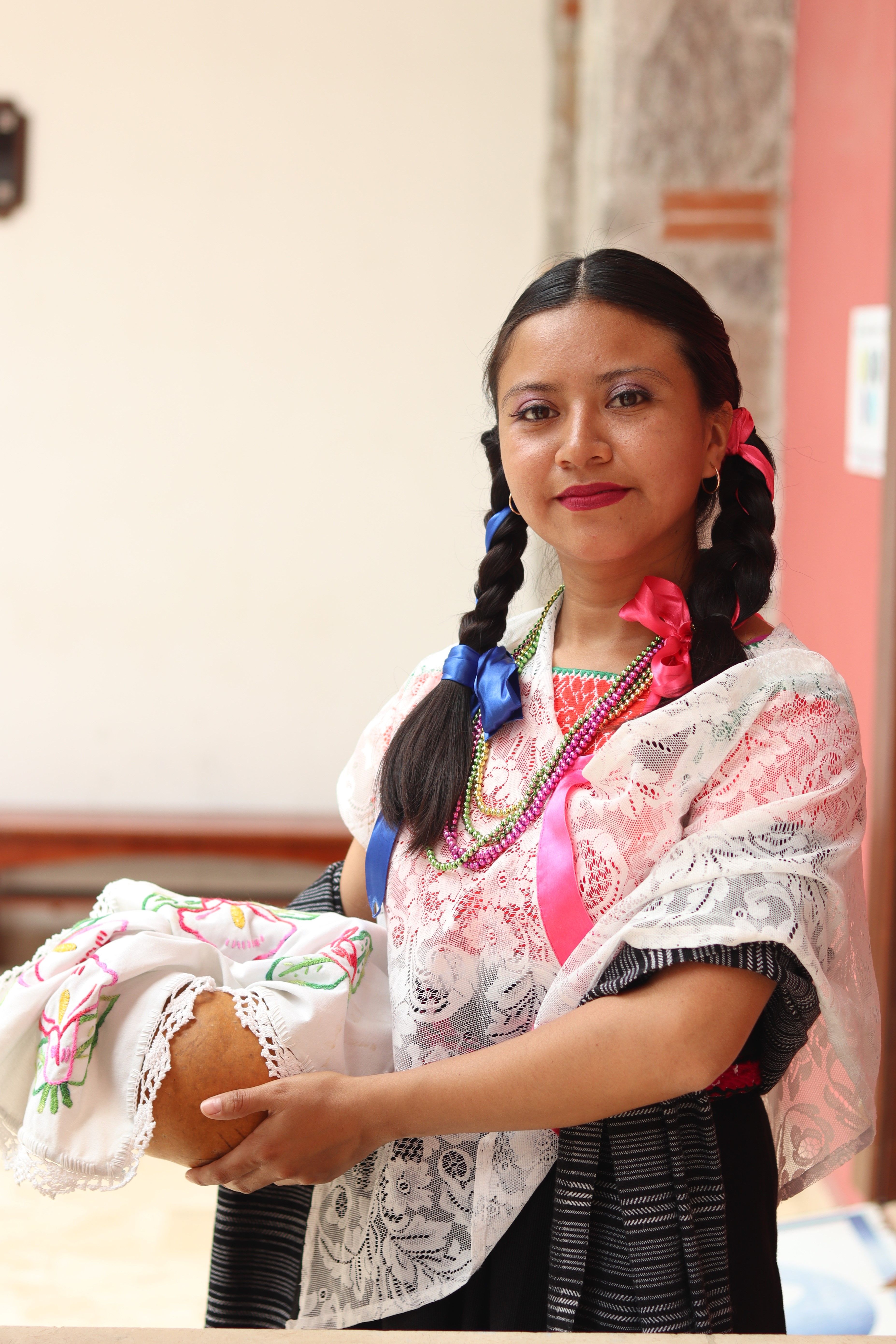 Portrait of a woman in traditional clothing holding bread, showcasing cultural heritage.
