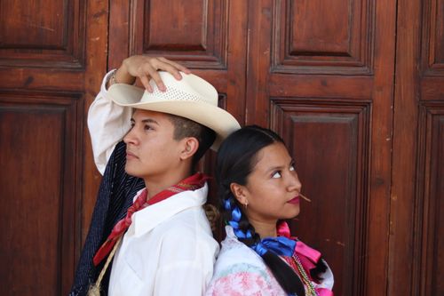 Free A couple in traditional Mexican attire posing creatively against a wooden background. Stock Photo