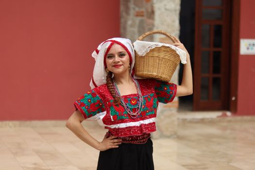 A woman dressed in vibrant traditional attire holding a basket, showcasing cultural heritage.