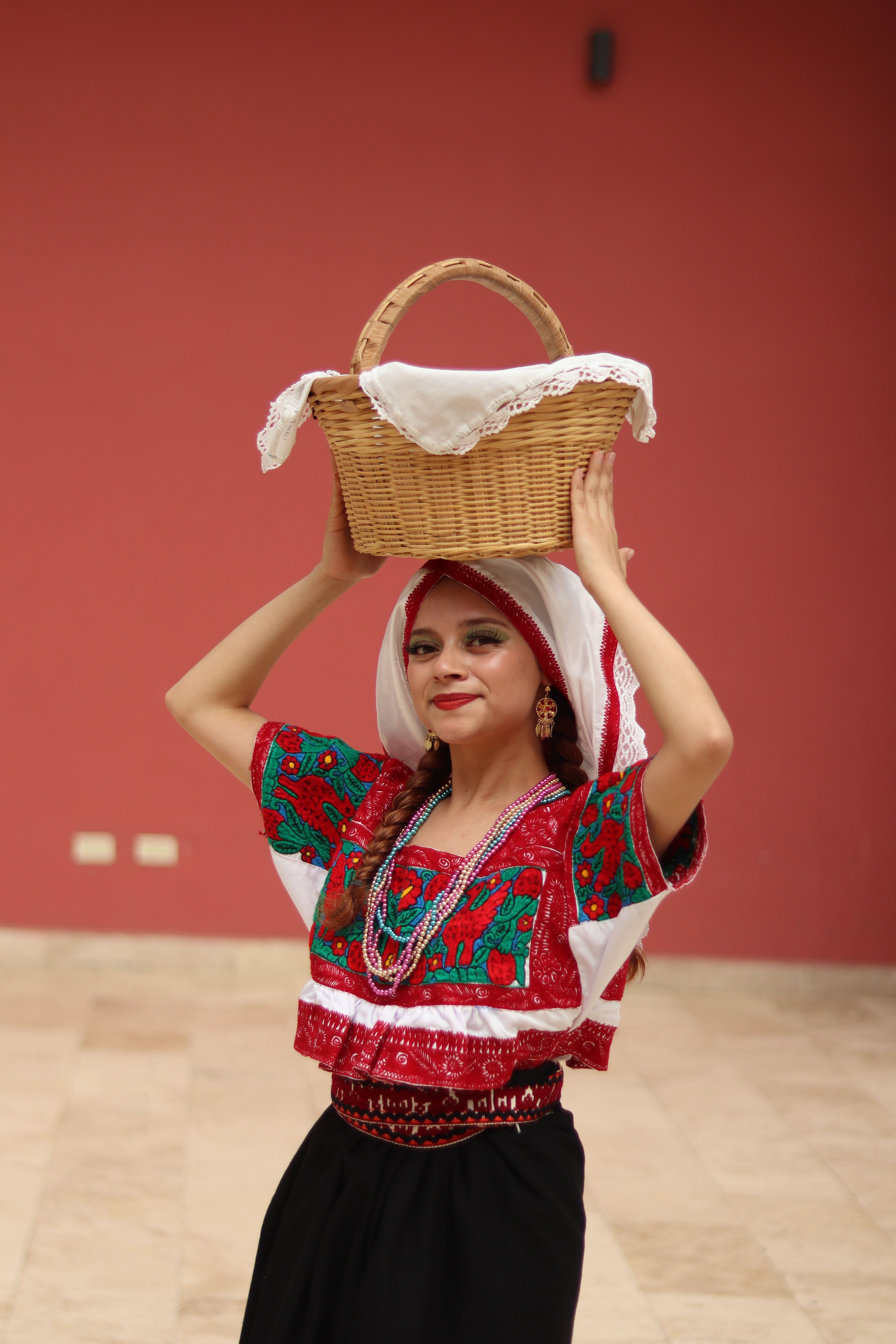 Woman in vibrant Mexican attire with a wicker basket, embodying traditional culture.