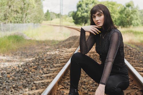 Foto Van Vrouw In Zwarte Outfit Squat Poseren In Het Midden Van Treinspoor