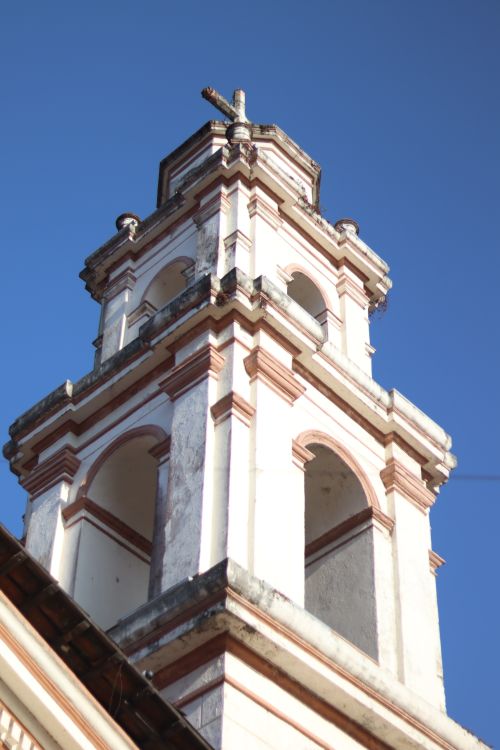 Free A close-up view of an ornate church bell tower under a clear blue sky. Stock Photo