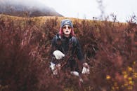 在户外荒野中，一位紫发时尚女子身着冬装