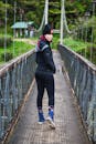 一名妇女自信地走过一座吊桥，桥周围环绕着郁郁葱葱的绿化植物