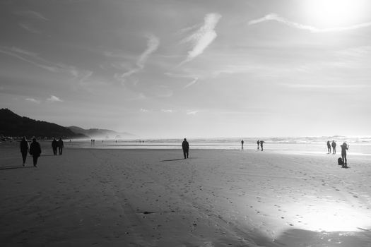 People strolling on Cannon Beach in Oregon, captured in a serene black and white composition.
