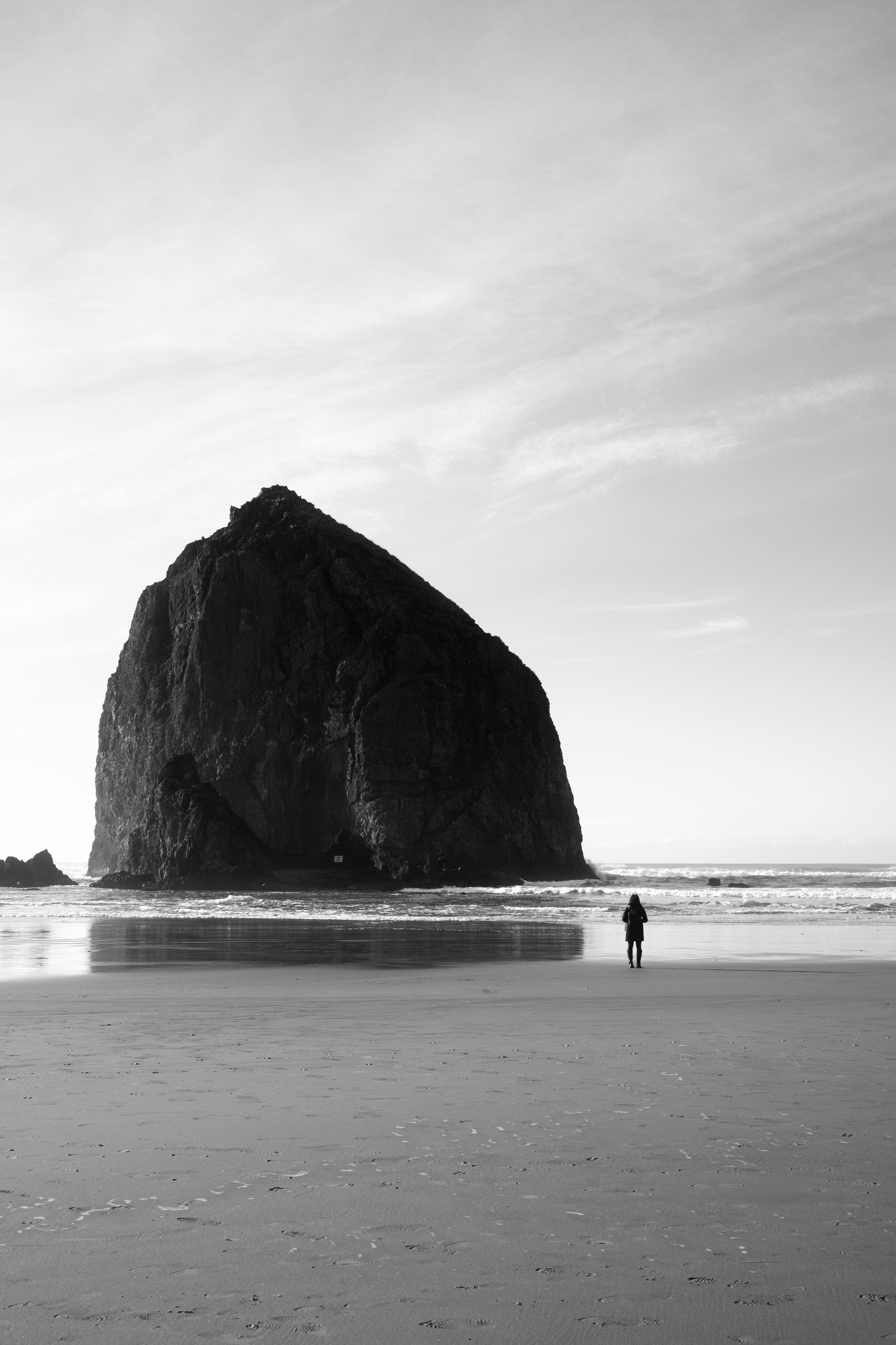 person standing near rock formation on sea shore in oregon