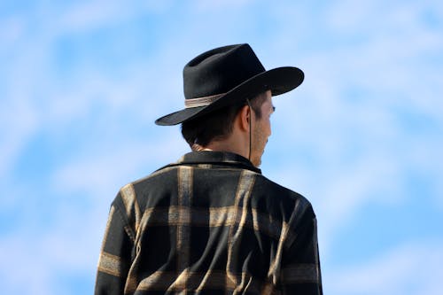 A man in a cowboy hat is looking at the sky