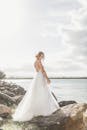 黄金时段，新娘身着惊艳礼服，优雅地在海边的岩石上摆姿势