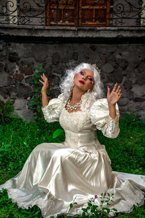 A woman in white dress sitting on grass