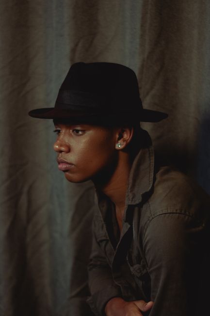 Elegant portrait of a man wearing a fedora, showcasing contemplative fashion style.