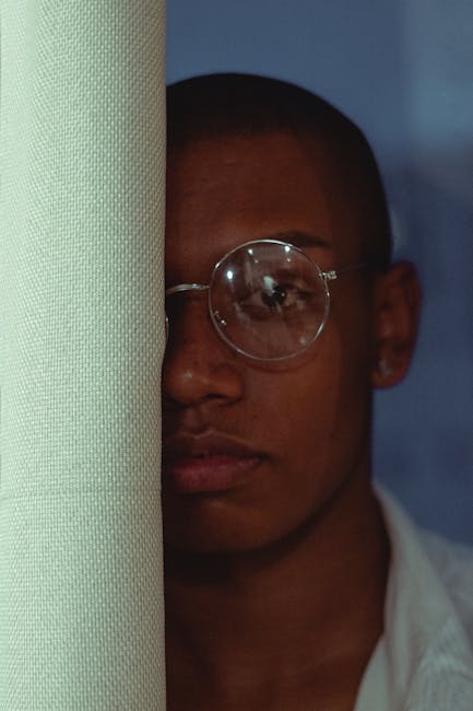 Close-up portrait of a man with eyeglasses, showcasing modern fashion and serious expression.