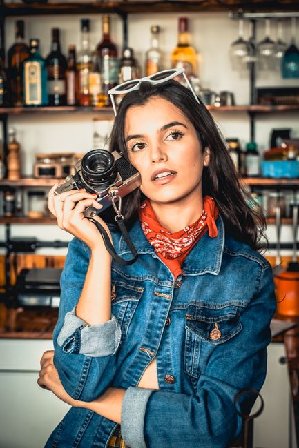 Stylish young woman with a retro camera in a trendy café setting, exuding cool vibes.