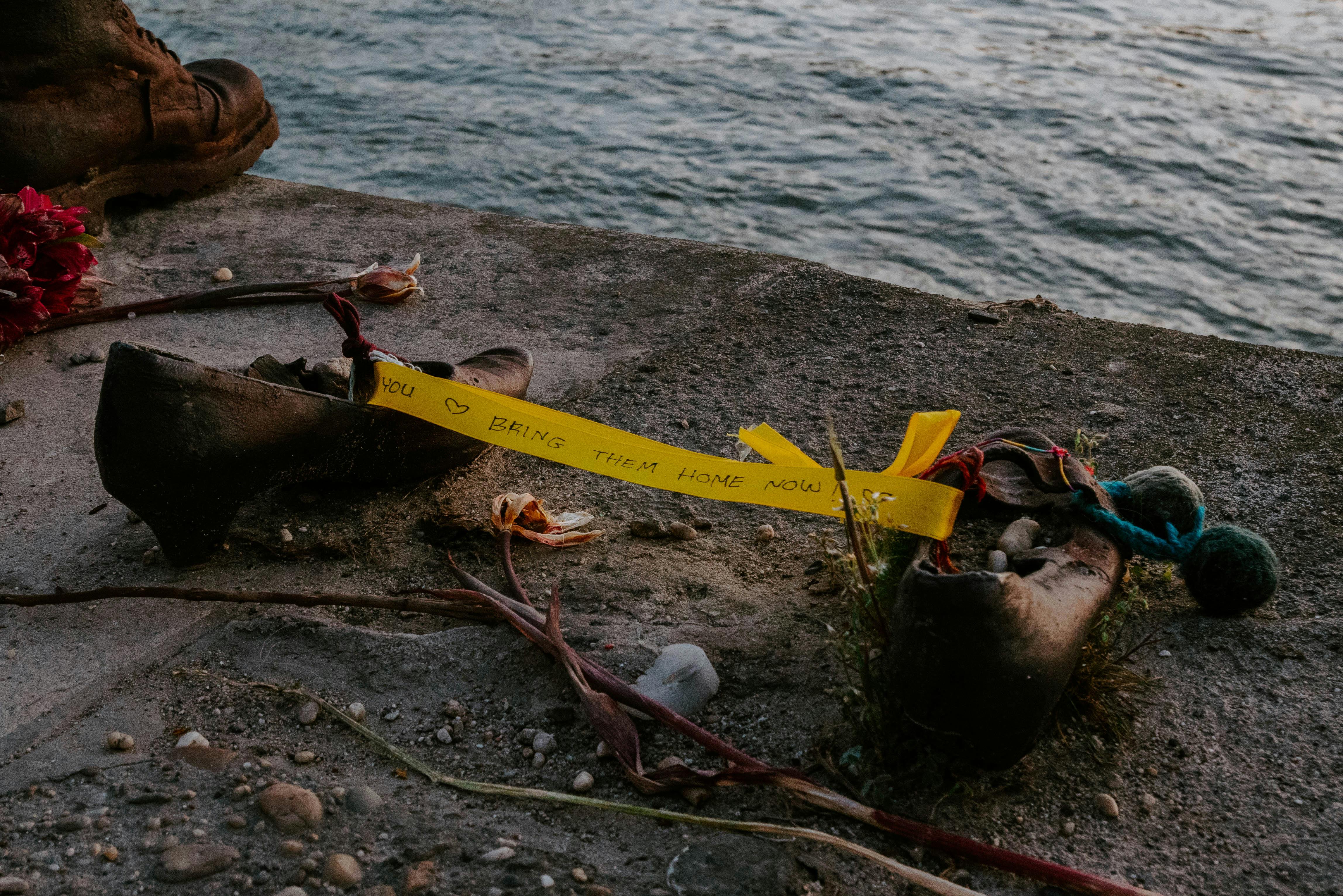 A moving memorial on the Danube riverbank in Budapest with shoes and a heartfelt message.