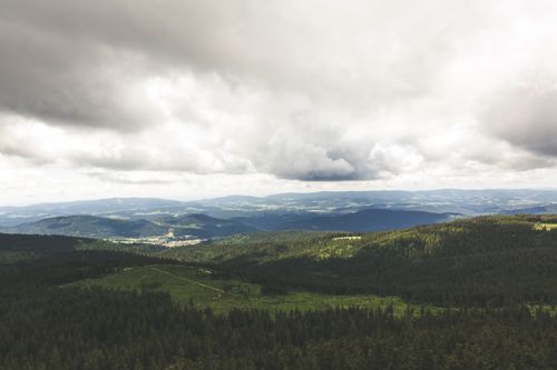 Free Beautiful aerial view of a lush forest and mountain range under a cloudy sky. Stock Photo