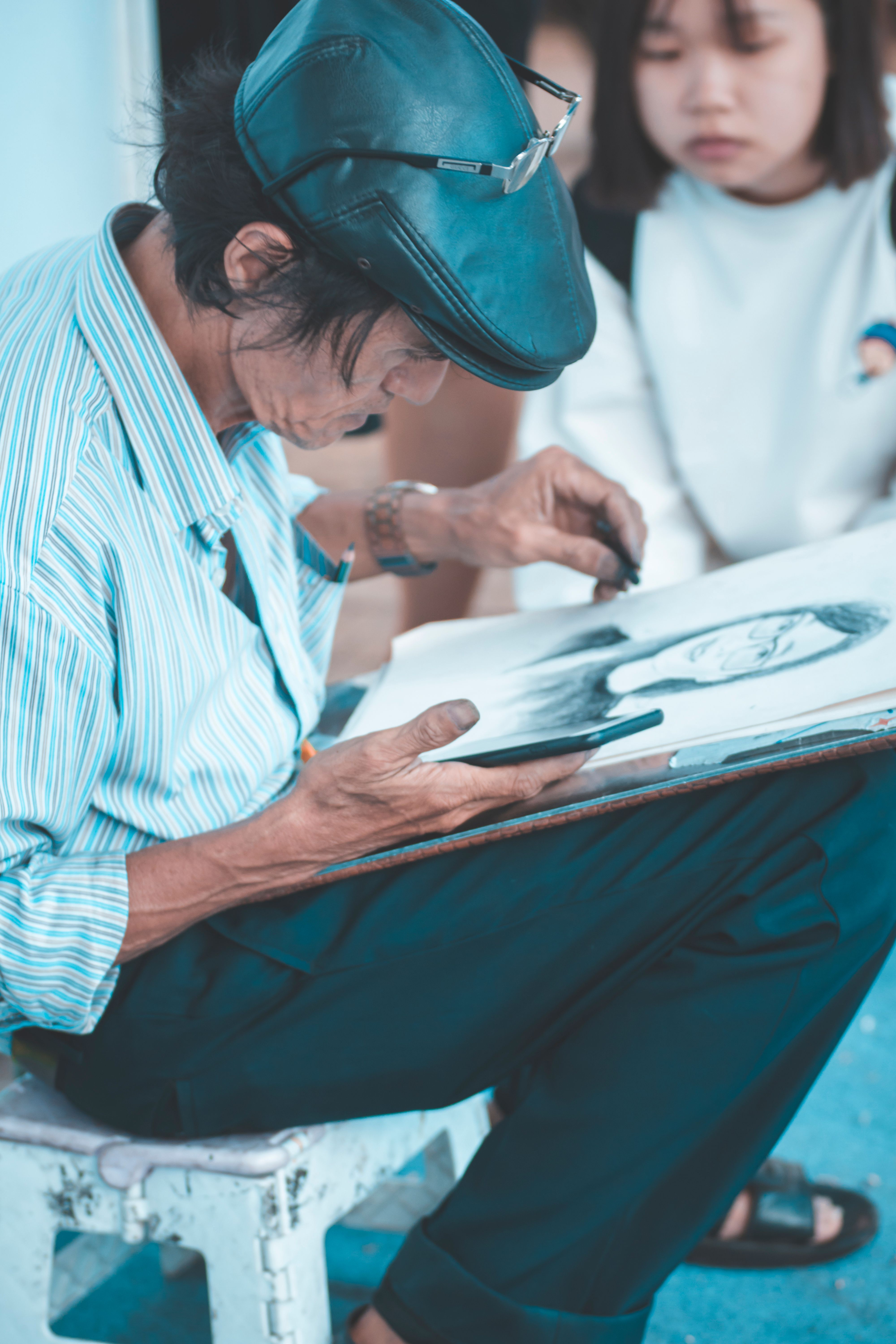 A skilled street artist intensely sketching a portrait with a charcoal pencil.