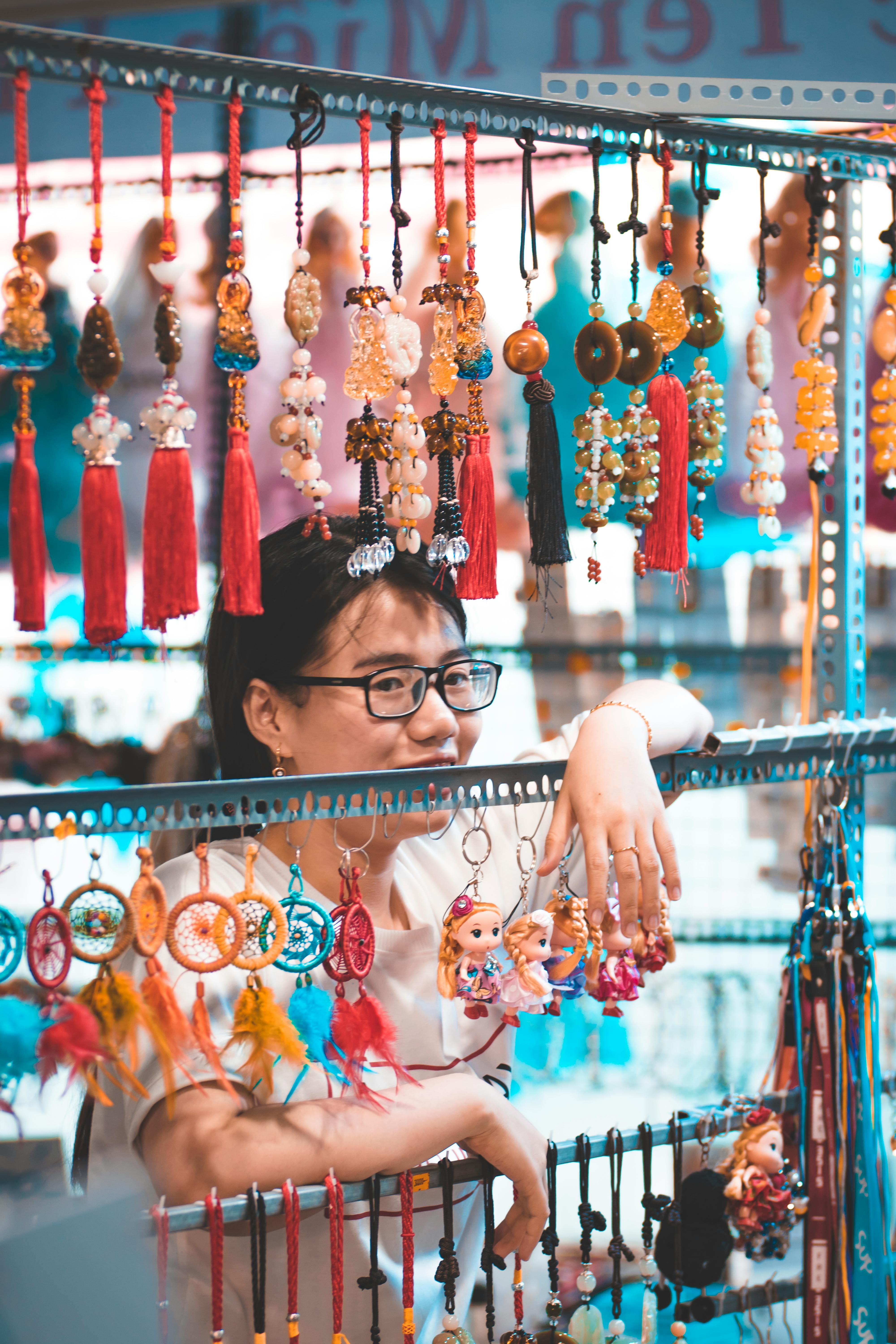 亚洲妇女在市场的摊位上出售色彩鲜艳的悬挂装饰品